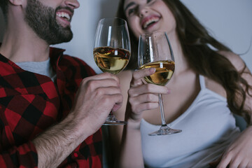 selective focus of young couple laughing while holding glasses of white wine