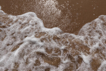 Gentle wave on sandy beach. Sun, sand and the sea to make summer holiday perfect. Sun reflexes in water and wet sand.