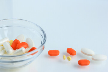 Multicolored pills, tablets against the virus, flu, disease, a thermometer and a syringe on light...