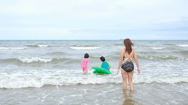 Mother and children playing in the sea
