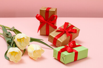 Gift boxes with tulip flowers on a pink background.