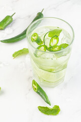 cocktail with cucumber, chili and ice on a white background.