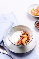 Healthy breakfast yogurt bowl with granola and caramelized bananas and nuts on grey concrete background. Selective focus