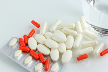 Multicolored pills, tablets against the virus, flu, disease, a thermometer and a syringe on light...