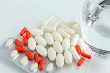 Multicolored pills, tablets against the virus, flu, disease, a thermometer and a syringe on light...