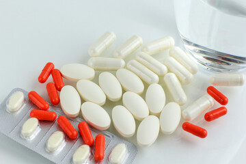 Multicolored pills, tablets against the virus, flu, disease, a thermometer and a syringe on light...