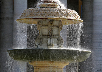 Ancient fountain at St Peter's square in Rome with dome background, crystallized water.