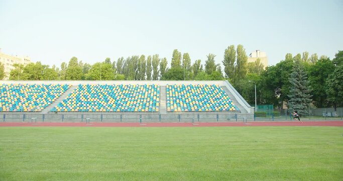 Side view of caucasian female athlete practicing at a sports stadium, hurdling on running track, slow motion. Track and Field Sports Training in Stadium.