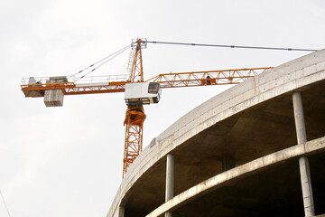 Fototapeta premium Construction crane near concrete building.