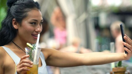 Young woman taking photo of coffee with cellphone in cafe