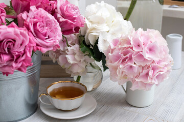 Bouquets of hydrangea, roses and a cup of tea between them.