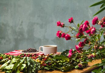 Coffee beans, coffee berries and a cup of coffee on the table.