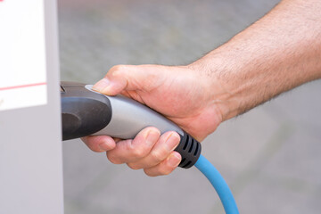Man hand holding an electric vehicle charging connector