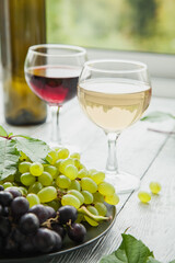Two glasses with different varieties of wine and a plate with different ripe grapes. The concept of wine tasting