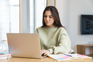 Photo of perplexed student woman using laptop while doing homework
