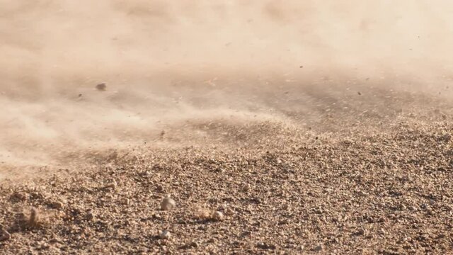 Close up of bike wheel break with dry sand flying away, slow motion