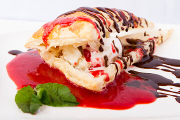 Dessert with ice cream, mashed strawberries and chocolate from the the side close up