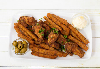 Fried chicken wings and fired bread with sauce and green olives top view