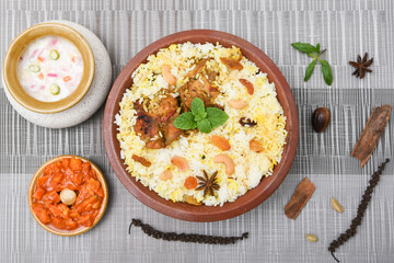 Spicy and delicious chicken biryani in traditional clay pot. Malabar biryani or Hydrabadi chicken biryani, Dum Biriyani, Chicken pulao basmati rice, herbs, raitha for Ramadan Kareem, Eid-Ul-Adha