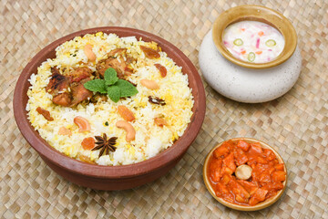 Spicy and delicious chicken biryani in traditional clay pot. Malabar biryani or Hydrabadi chicken biryani, Dum Biriyani, Chicken pulao basmati rice, herbs, raitha for Ramadan Kareem, Eid-Ul-Adha