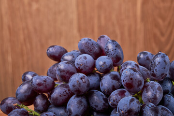 fresh ripe red grapes on a wood texture surface. Ancient style, beautiful background with a branch of blue grapes. Red grape. Dark grapes