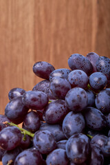 fresh ripe red grapes on a wood texture surface. Ancient style, beautiful background with a branch of blue grapes. Red grape. Dark grapes