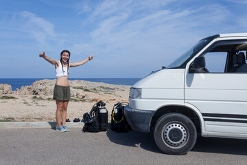 Wanderlust concept of a young woman traveling with a van and preparing to go has scuba diving on Majorca island.