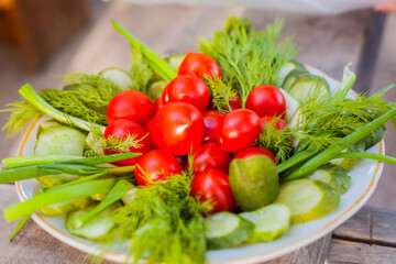 Small tomatoes with cucumbers and lettuce on the background of wood.