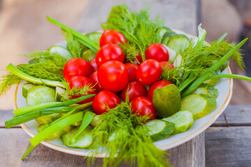 Small tomatoes with cucumbers and lettuce on the background of wood.