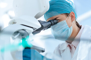 female scientist looking carefully through a microscope.