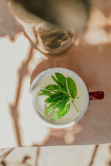 Round white cup of mint tea on a beige blurred background