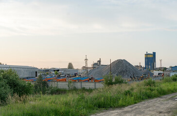 A large cement plant in the country near the railway. Pipes, tanks, trucks, tractors.