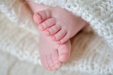 Baby feet on wrapped in white blanket. Gentle fingers close up view.