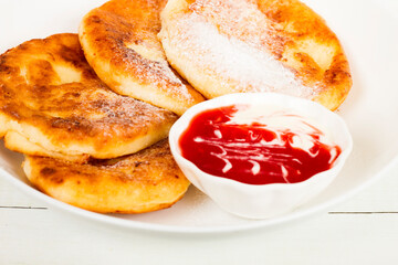 Pancakes on a white plate with mashed strawberies close up