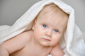 Cute little baby at home in bed covered with white blanket. Beautiful cute baby girl.