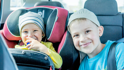 Two brothers in car smiling and enjoying togetherness. Two child boys looking into camera 