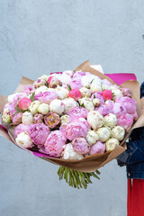 Huge bouquet with pink and white peonies held by a girl florist. 