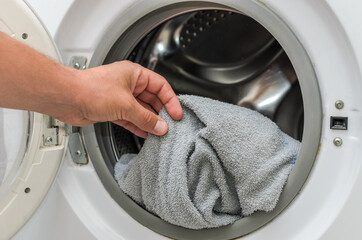 Housekeeper throws dirty clothes into the washing machine