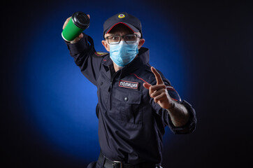 the guy in the police uniform is a Russian police officer in a medical mask with a coffee Cup in...