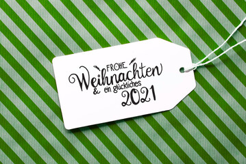 Label With German Calligraphy Frohe Weihnachten Und Ein Glueckliches 2021 Means Merry Christmas And A Happy 2021. Green Wrapping Paper As Background