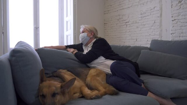 Depressed senior old woman crying on couch with pet dog as only Companion. Sad and tired widower amid COVID-19 pandemic. Coronavirus death, lockdown, social distancing and Mental health.