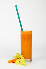 Carrot and celery juice in glass with a blue green straw