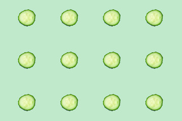 Regular seamless pattern of cucumber slices on a mint background.Photo collage. Food blog, vegetable background. Printing on fabric, wrapping paper.Top view.