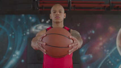 Portrait of concentrated athletic bald african american basketball player holding basketball between hands on indoor court, expressing determination, confidence and readiness for competition.