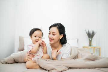 Beatuful mother playing with daughter. Little girl have fun at home.