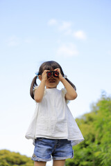 オペラグラスを使う幼児(5歳児)と青空