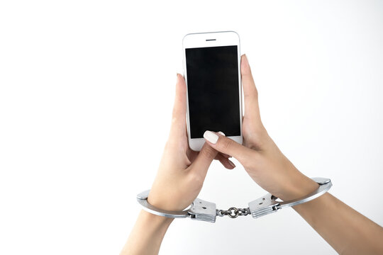 woman's hands in handcuffs holding smartphone on isolated white background, virtual reality concept, social media addiction, nomophobia
