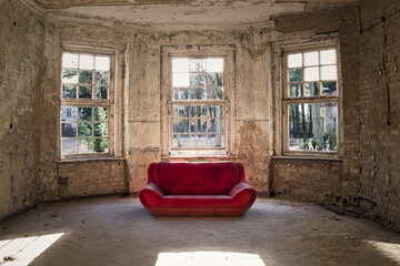 An old red sofa in the empty room of the abandoned mansion