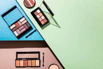 top view of eye shadow palettes and double-sided eyeshadow applicators on blue, green and pink
