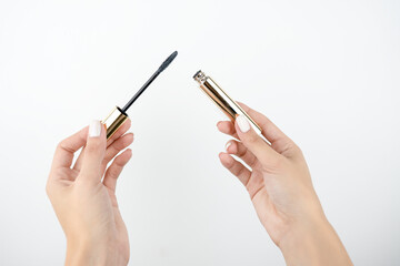 woman's hand holdingeye maskara to apply on lashes, isolated white background, makeup and beauty...